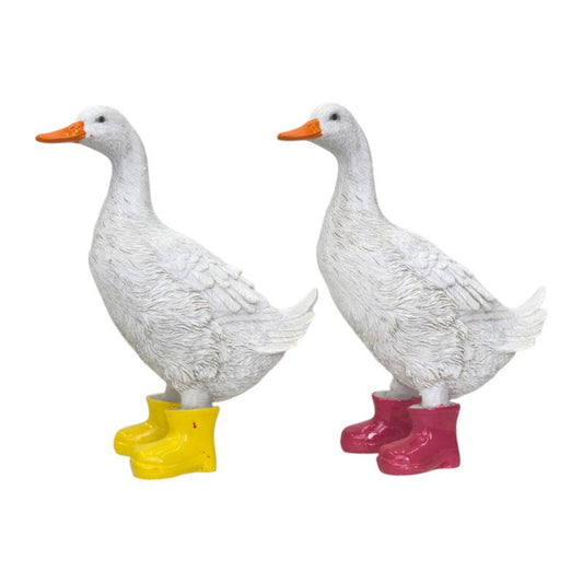 Two white duck figurines standing on colorful rubber boots, shown side by side against a plain white background. One duck wears yellow boots and the other wears pink boots.